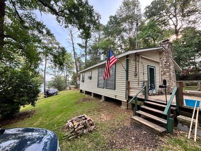 A cozy cabin with an American flag surrounded by trees and greenery.