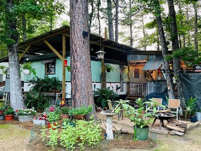 Cozy outdoor garden and seating area by a cabin in the woods.