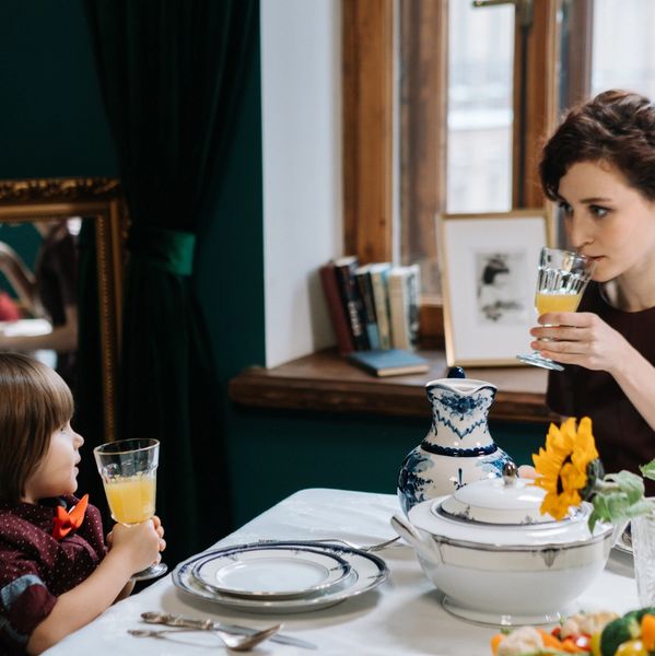 A woman and child enjoy orange juice at a beautifully set dining table with elegant dishes.