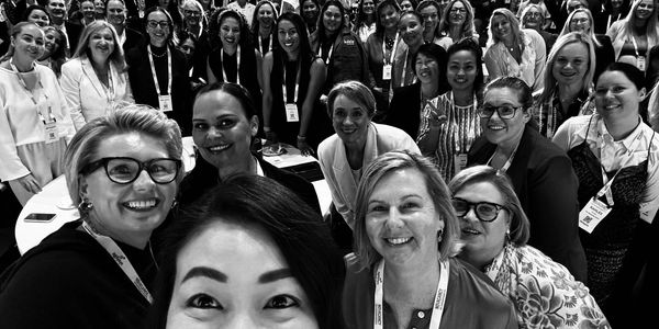 Group of diverse women smiling for a selfie at an event.