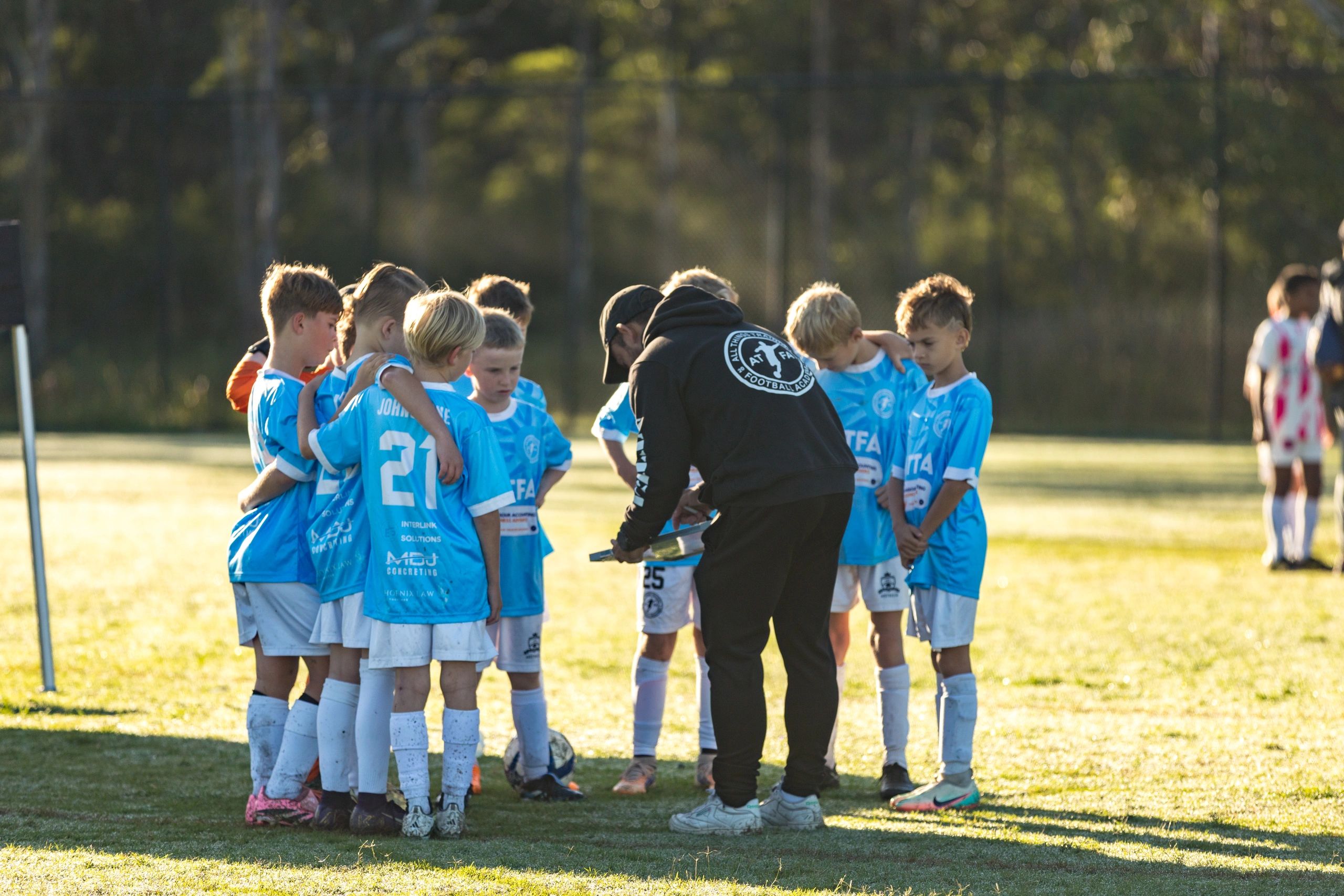 Youth soccer team huddled around coach for strategy talk.