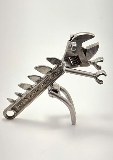 A dinosaur sculpture made from metal wrenches and tools.