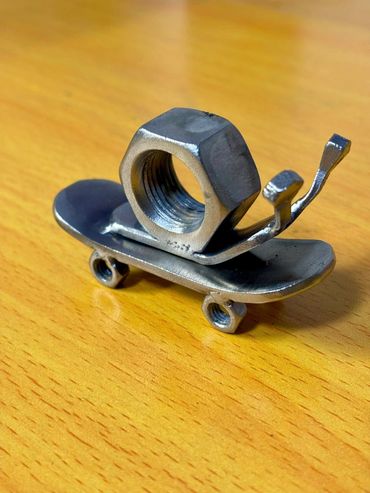 A miniature skateboard sculpture made from metal nuts and bolts.