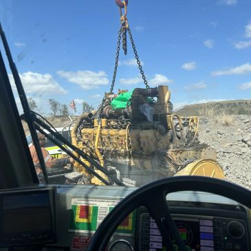 Engine being lifted by a crane at a construction site.