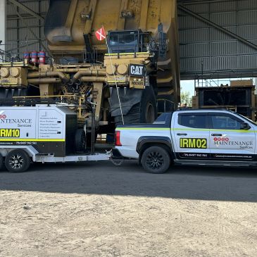 Maintenance truck and trailer parked near large heavy machinery.