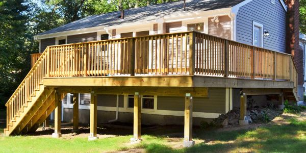 Newly built elevated wooden deck attached to a house with stairs.