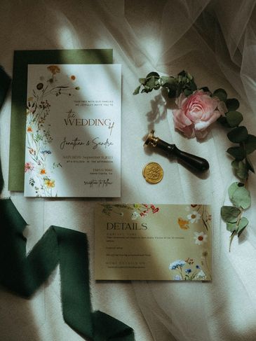 Elegant wedding invitation setup with flowers and wax seal.