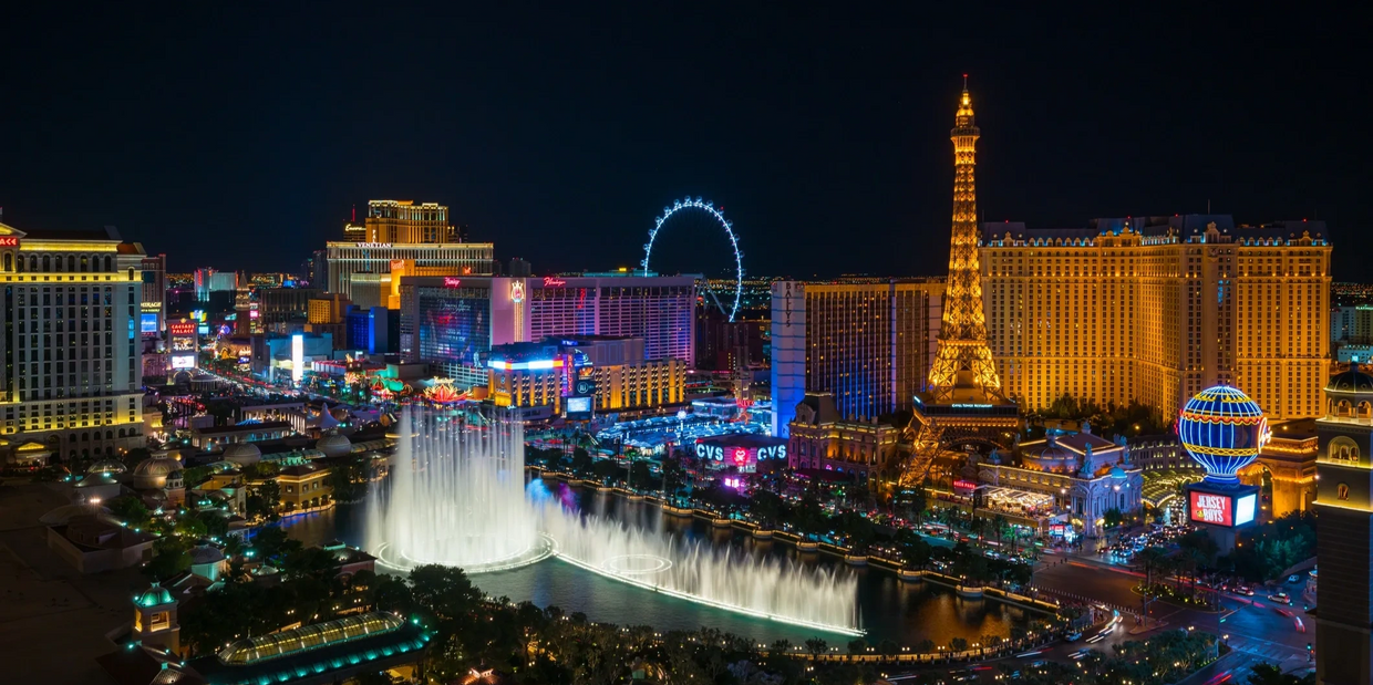 Las Vegas Strip at night with fountains and illuminated Eiffel Tower replica.