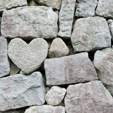 Heart-shaped stone among regular stones in a wall.