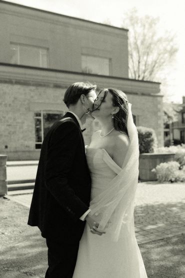 A bride and groom share a tender moment outdoors on their wedding day.