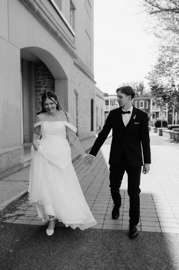 Bride and groom holding hands, walking outside on their wedding day.