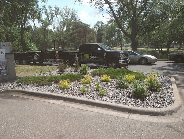 Commercial parking lot landscape planting bed with decorative rock and shrubs