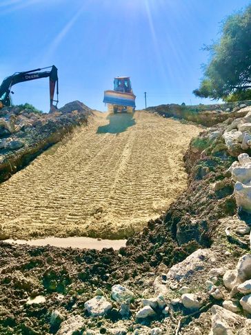 Tractor creating road on a hill. This road will hold up over time to all weather and water. 