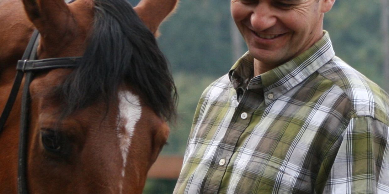 Man smiling next to a brown horse.