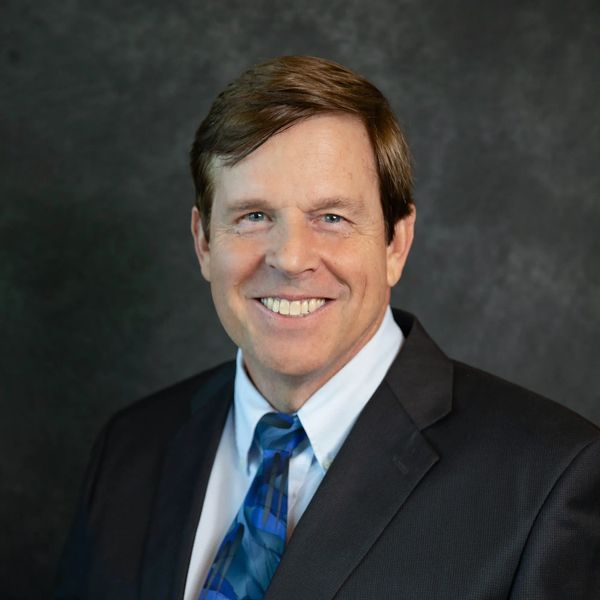 Keith Dorson, Company Founder, shown wearing a suit and a blue tie, with a big smile. 