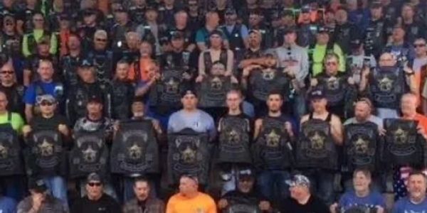 Large group of people wearing matching black vests with star logos posing together.