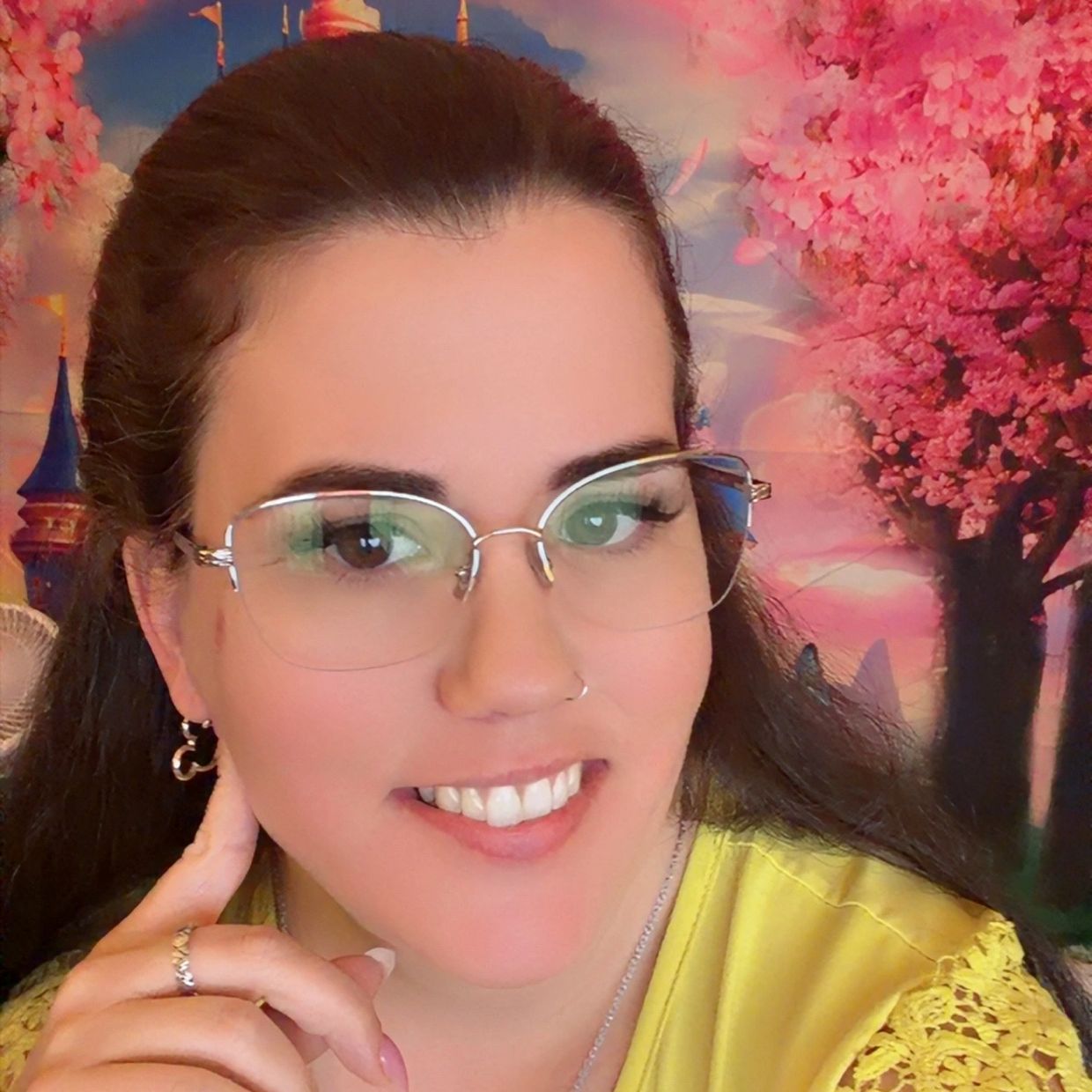 Woman with glasses smiling in front of a colorful fantasy castle backdrop.