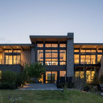 Modern house exterior with large windows at dusk.