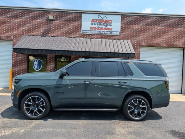 Gray SUV with tinted windows parked in front of a tint shop.