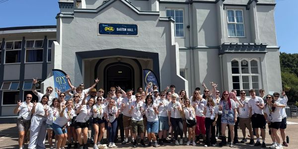Group of people posing outside Barton Hall on a sunny day.