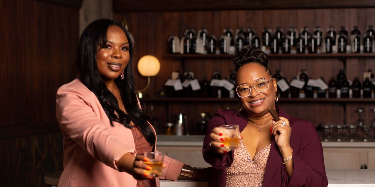 Owners & Partners Latosha and Ebony holding their drinks up to cheers.