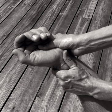 Two hands tightly gripping a wrist on wooden planks background.