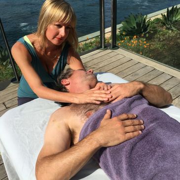 Woman giving a relaxing shoulder massage to a man outdoors.