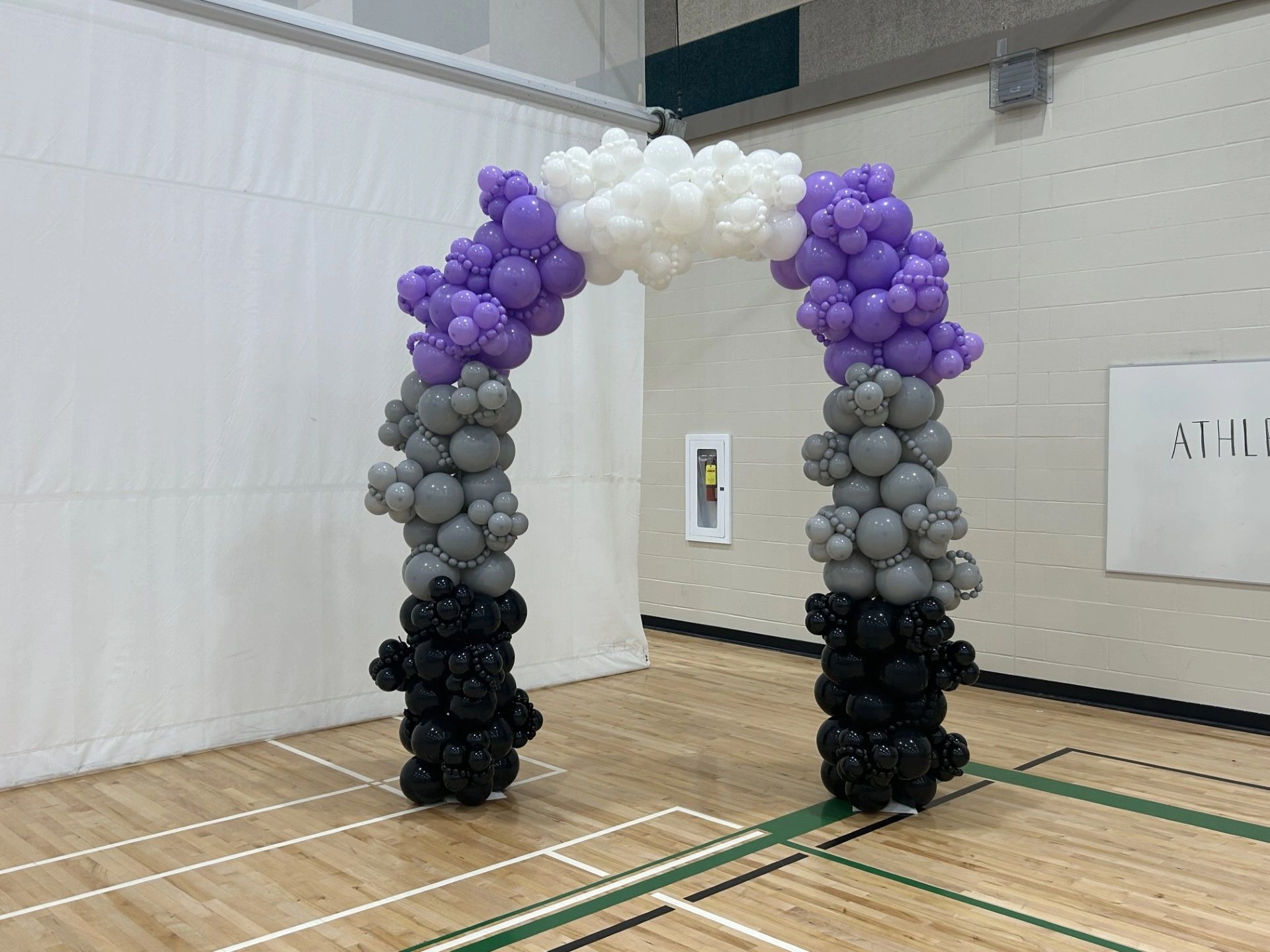 Colorful balloon arch in a gymnasium.