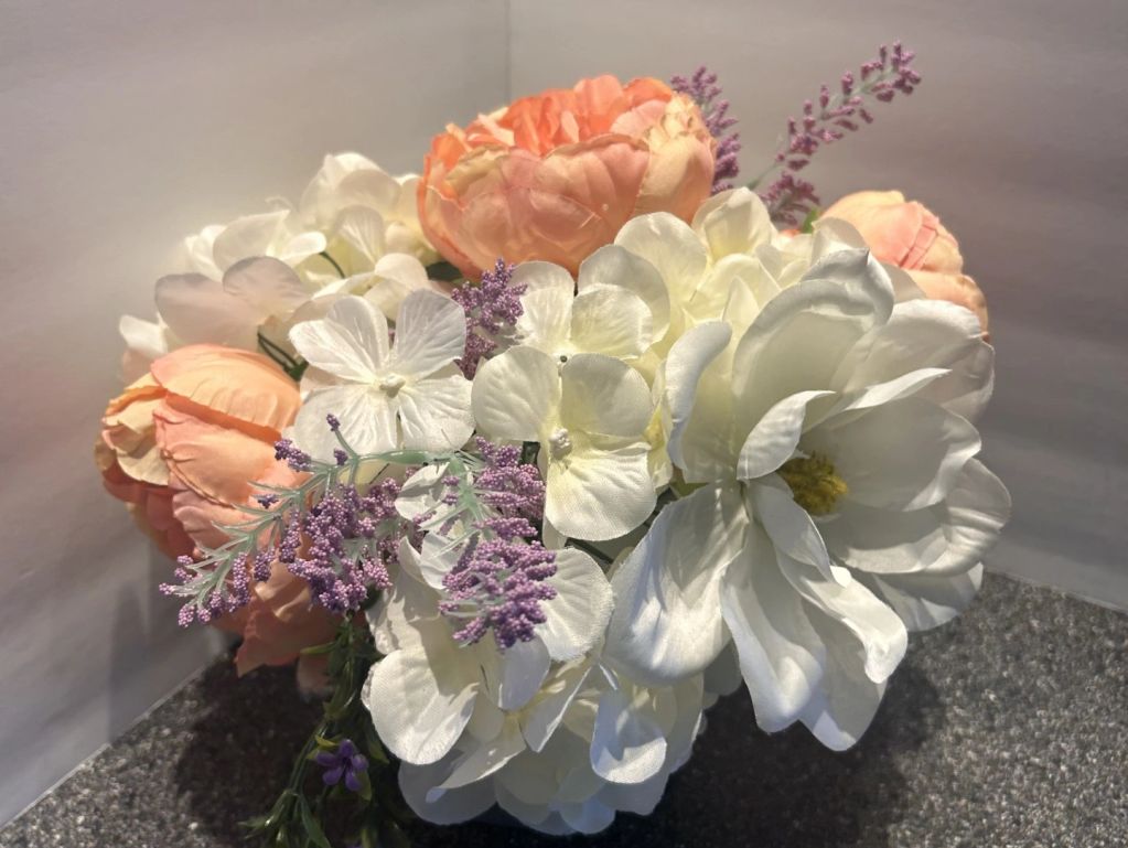 A bouquet of white, peach, and purple flowers.