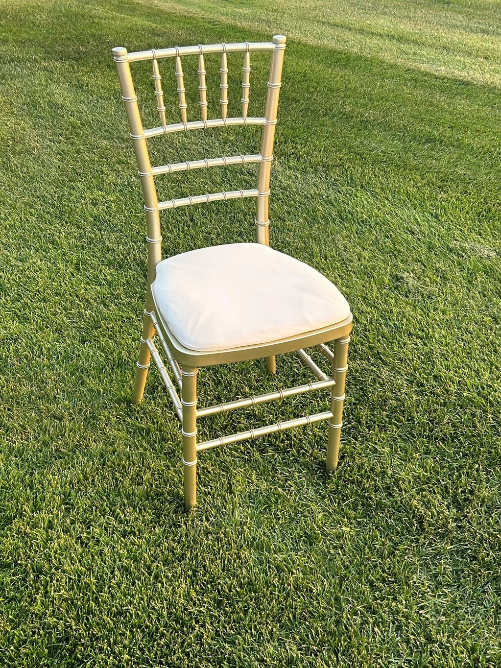 Champagne Chiavari chair with white cushion.