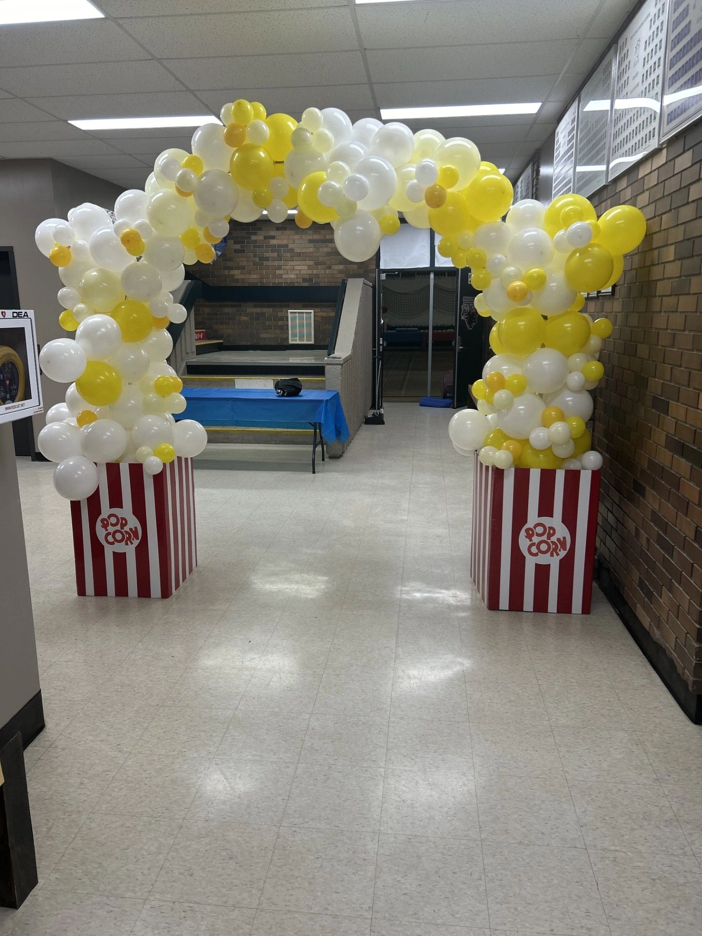 Popcorn-themed balloon arch in a hallway.