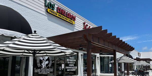 Outdoor seating area of Los Chilitos Mexican Grill under striped umbrellas.