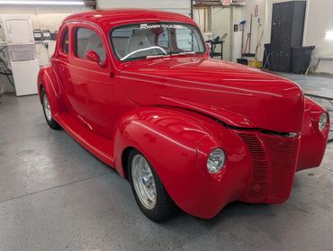 Shiny red vintage car in a garage with a decal on the windshield.