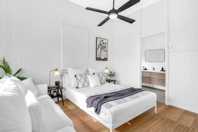 Bright white bedroom with modern decor and wooden flooring.