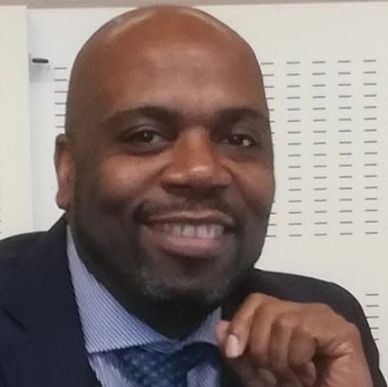 Smiling man in a suit and tie posing confidently.