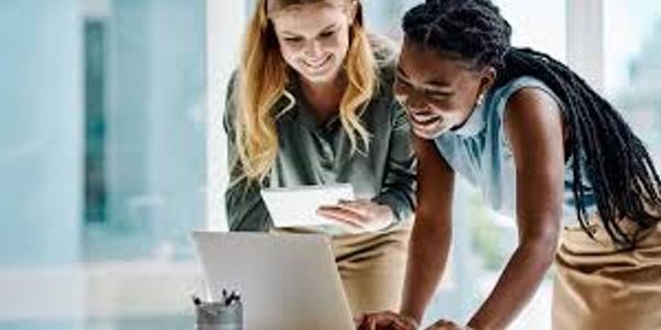 Two women happily working together at a laptop.