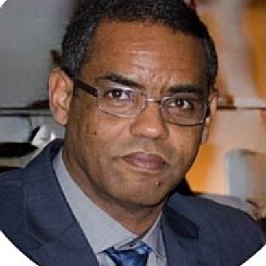Man wearing glasses and a suit looking at the camera.