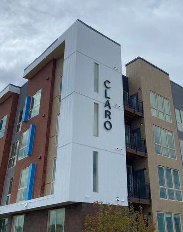 Modern apartment building named CLARO with multiple balconies and large windows.