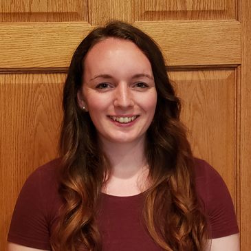 Young woman smiling in front of a wooden background.