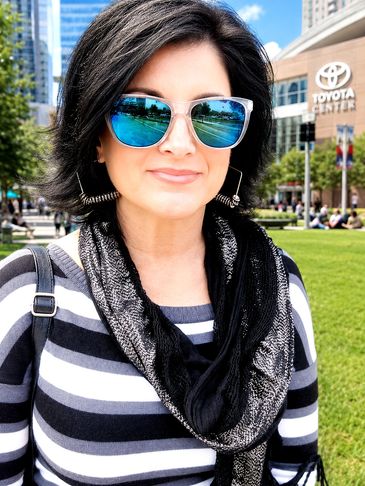 Woman wearing blue reflective sunglasses and striped shirt outdoors.
