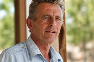 Portrait of a middle-aged man in a light blue shirt outdoors.