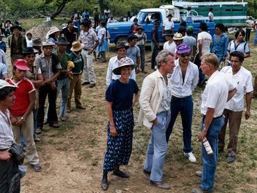 Group of people outdoors in casual and traditional attire, engaging in conversation.