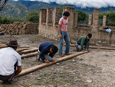 Four men working together on construction in a rural mountainous area.