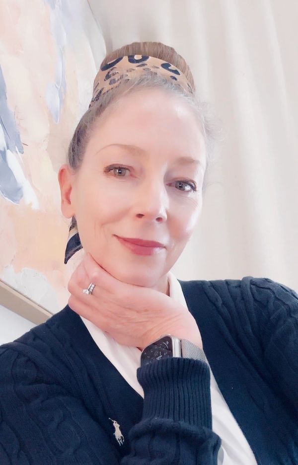 Woman with a headband and watch smiling at the camera.