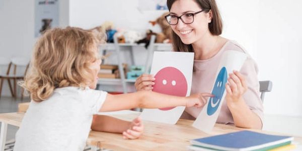 Child pointing at smiley face during therapy.