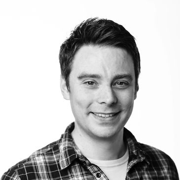 Smiling young man in a plaid shirt against a white background.