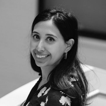Black and white portrait of a smiling woman with floral attire.