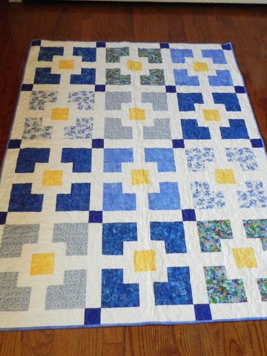 Colorful patchwork quilt with blue, yellow, and white blocks.
