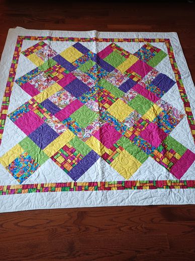 Colorful patchwork quilt with bright geometric patterns on a wooden floor.