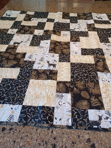 Black, white, and gold patchwork quilt with nature-themed patterns.
